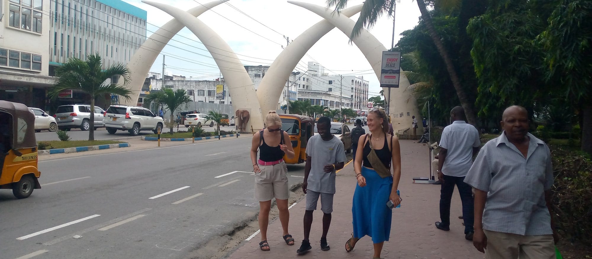 Travelers posing at Mombasa elephant tusks on Moi Avenue